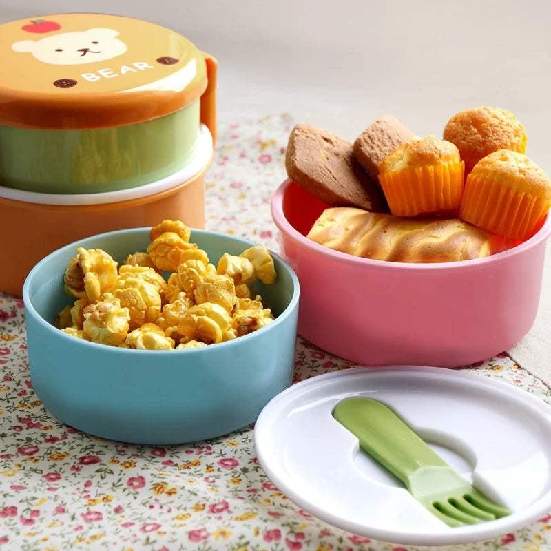 Colorful kawaii food containers with snacks on a floral tablecloth