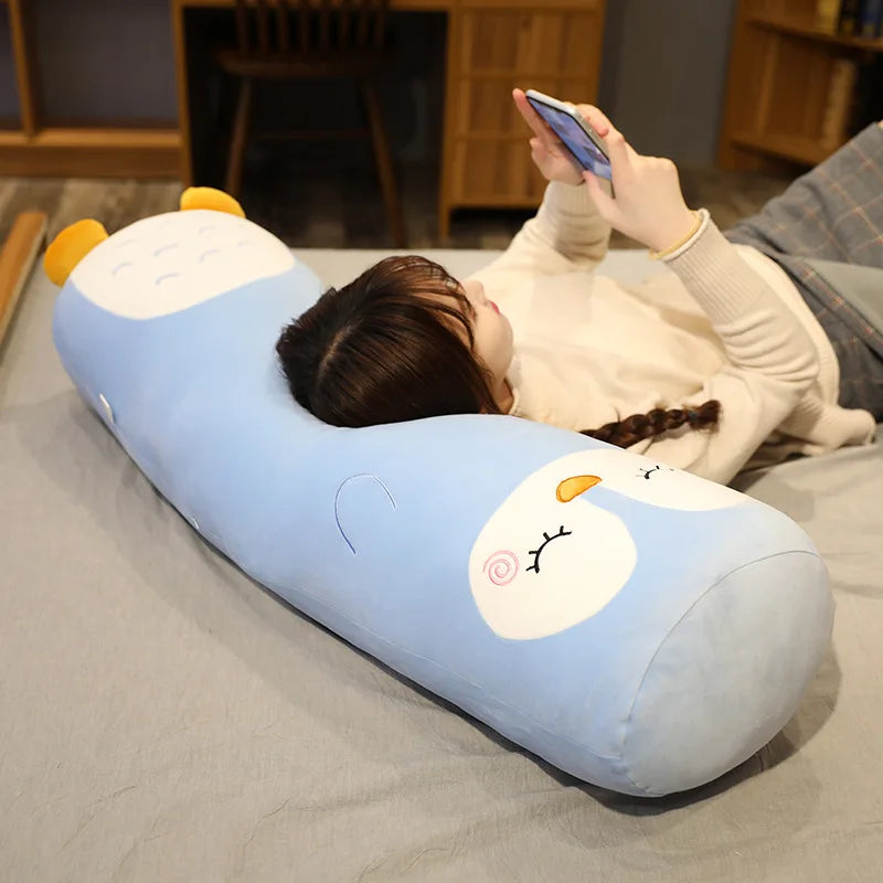 Person lying on a cartoonish blue kawaii pillow with a face, using a phone.