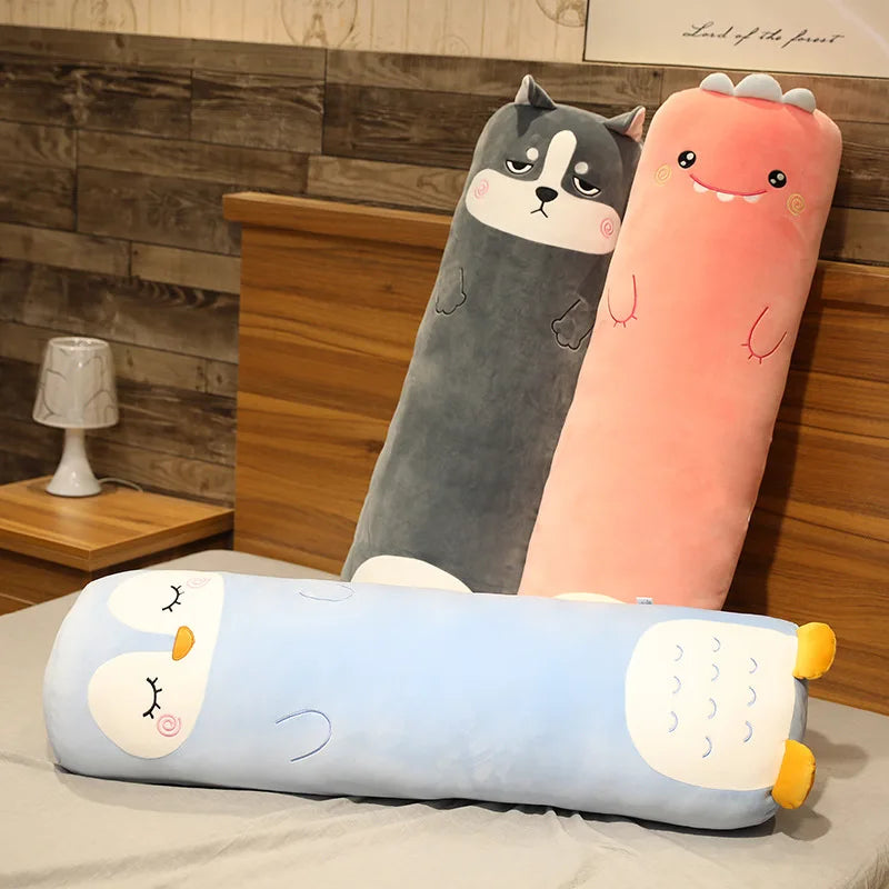 Three cartoon-style body kawaii pillows on a bed with a wooden headboard.