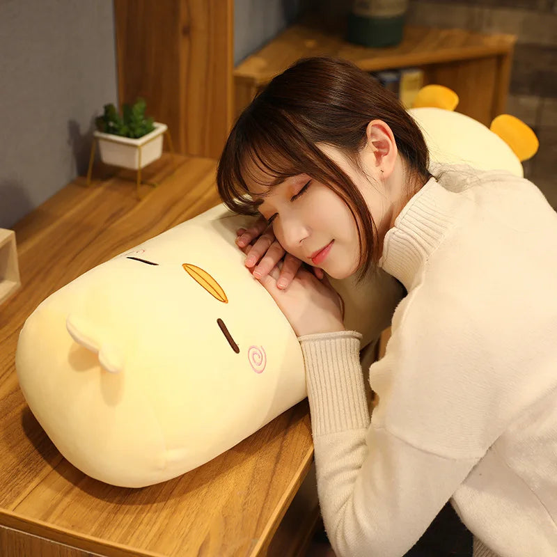 Woman lying on a large, plush, cat-shaped kawaii pillow in a cozy indoor setting.