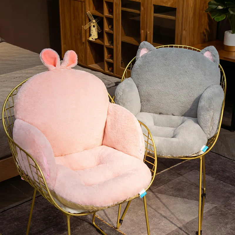Two kawaii plush animal-shaped cushions, one pink and one gray, on gold wire chairs in a room setting.