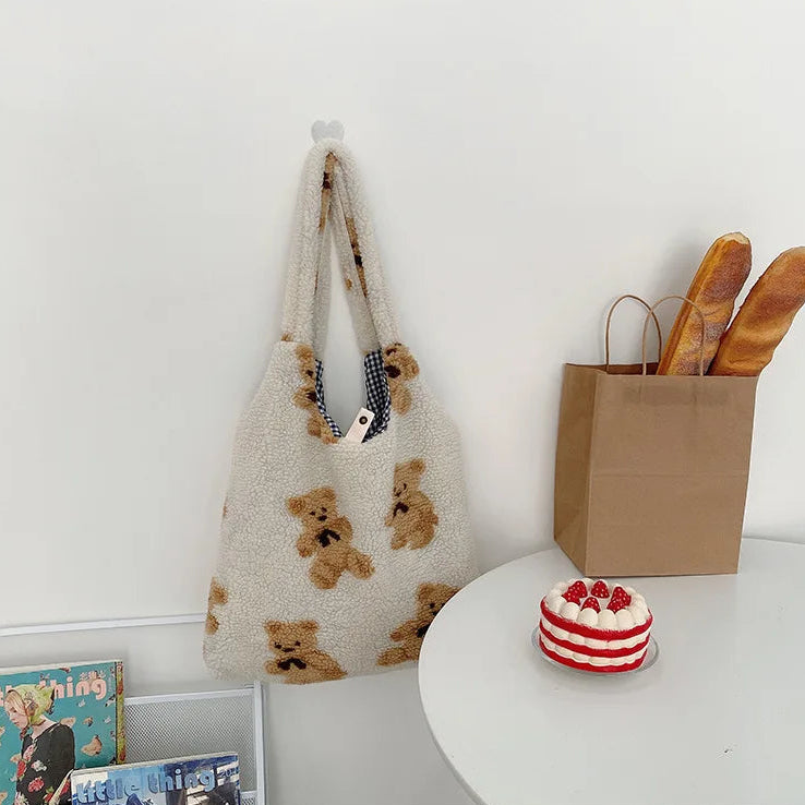 Tote bag with kawaii teddy bear pattern on a white surface with a cake and bread basket.