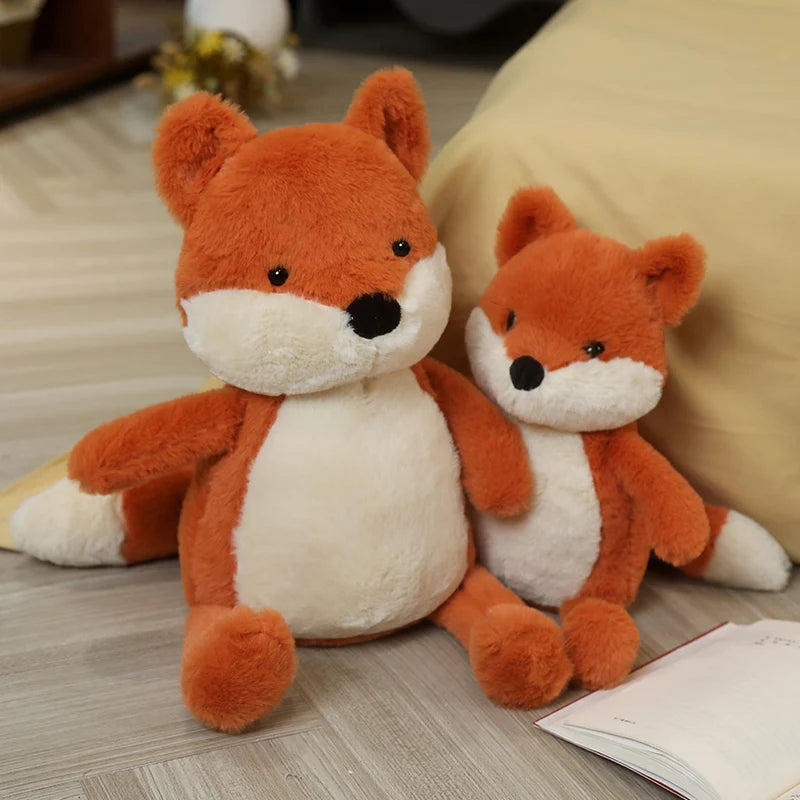 Two kawaii plush fox toys sitting on a wooden floor.
