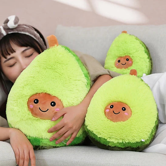 Person hugging avocado-shaped kawaii plush toys with smiling faces on a couch.
