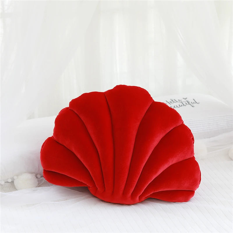 Red shell-shaped kawaii pillow on a white surface
