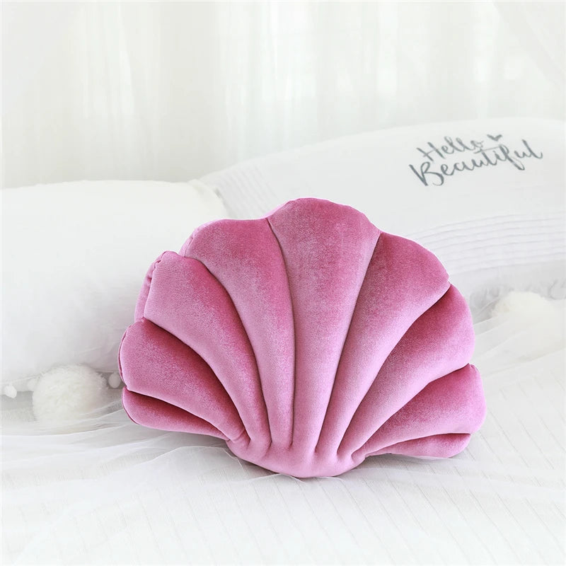 Pink shell-shaped kawaii pillow on a white surface with 'Hello Beautiful' text in the background.