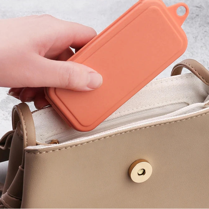 Hand holding an orange rectangular kawaii utensils above a beige handbag with text 'Can be carried with you, Convenient storage'.