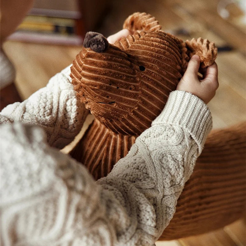 Person holding a brown kawaii teddy bear wearing a beige sweater.