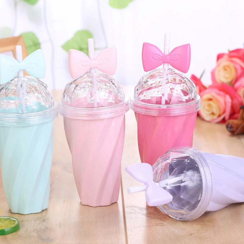 Colorful kawaii tumblers with lids and bows on a wooden surface.