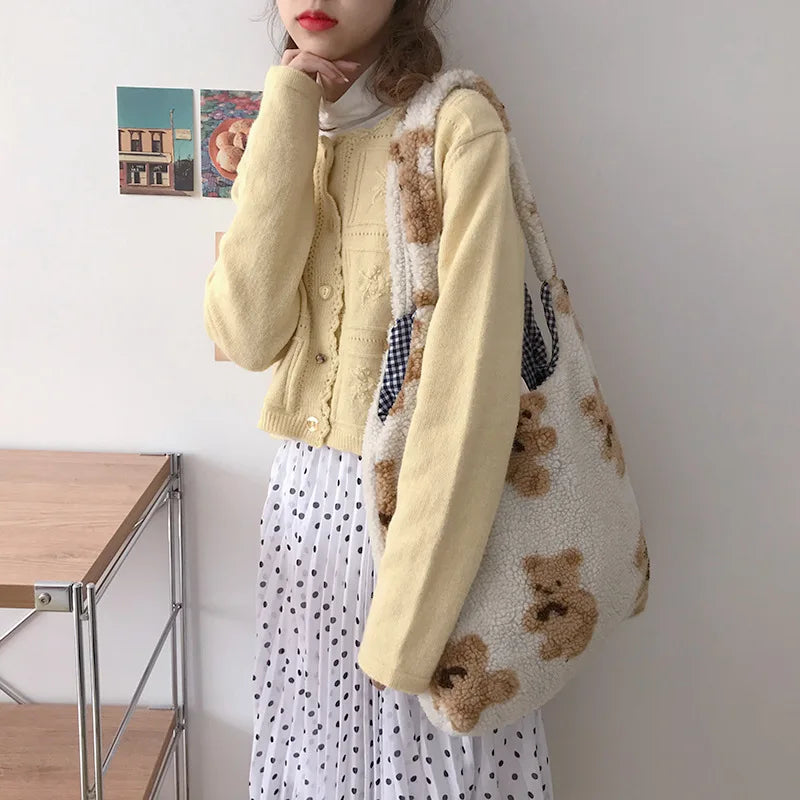 Person holding a tote bag with kawaii teddy bear design in a room setting
