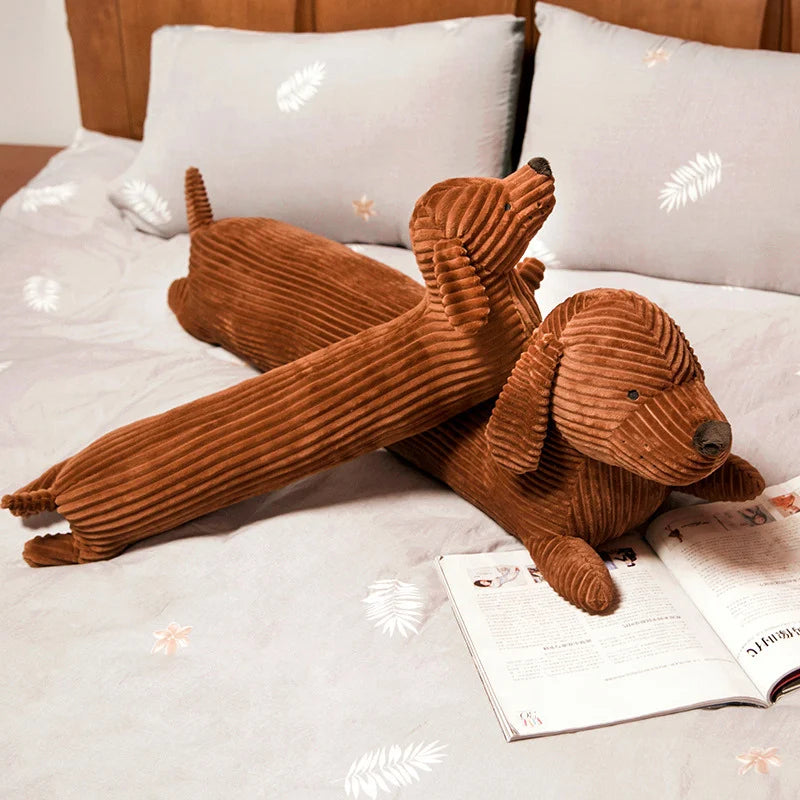 Brown corduroy dog-shaped kawaii pillow on a bed with a book underneath