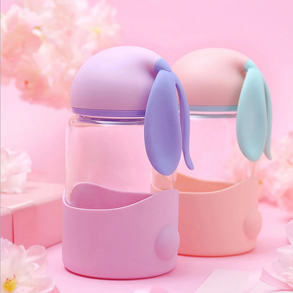 Two pink and purple kawaii water bottles with bunny ears on a soft pink background