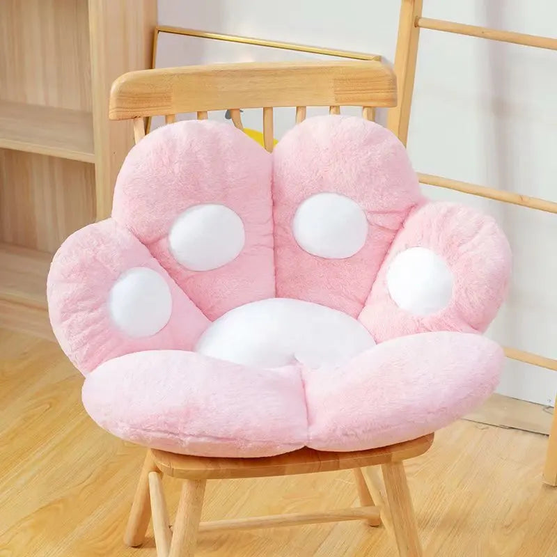 Pink paw-shaped kawaii cushion on a wooden chair with a light background