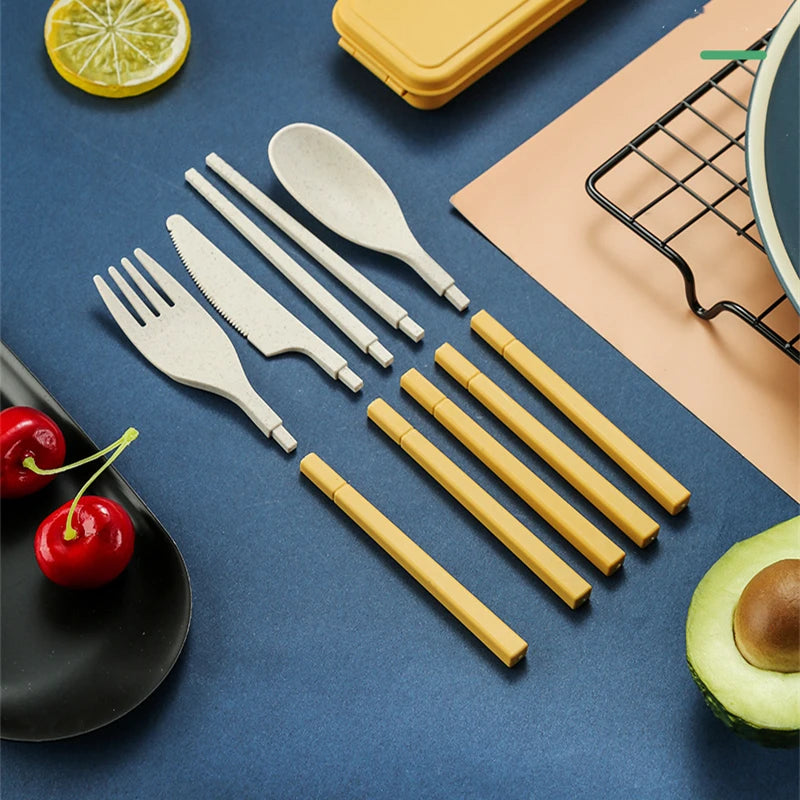 Set of kawaii utensils including forks, knives, and spoons on a blue surface with yellow straws and fruits.