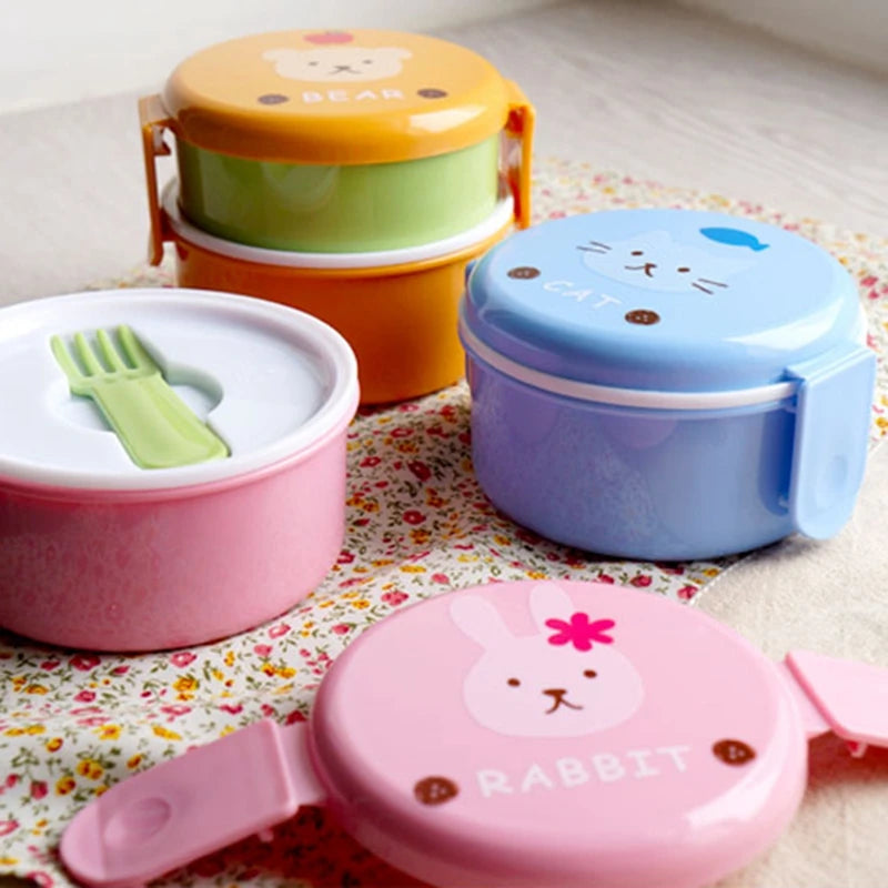Set of colorful children's kawaii lunch boxes with animal designs on a floral tablecloth.