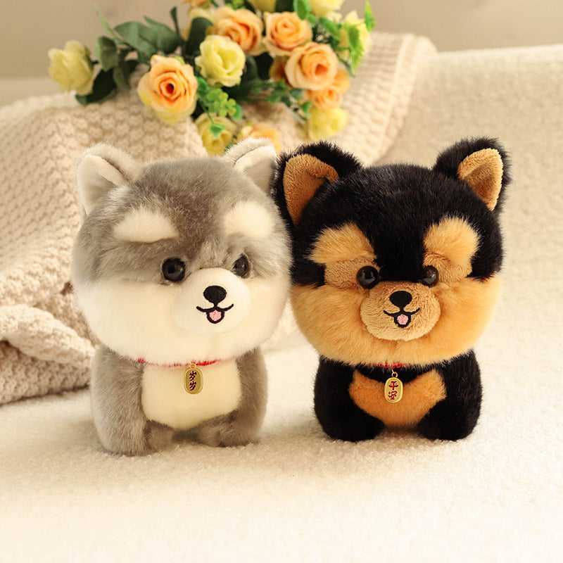 Two kawaii plush dog toys, one gray and white, one black and orange, sitting on a soft surface with flowers in the background.