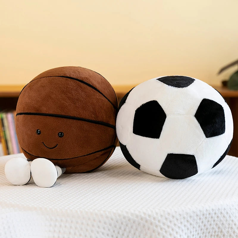 Kawaii plush toys shaped like a basketball and soccer ball on a white surface with a beige background.