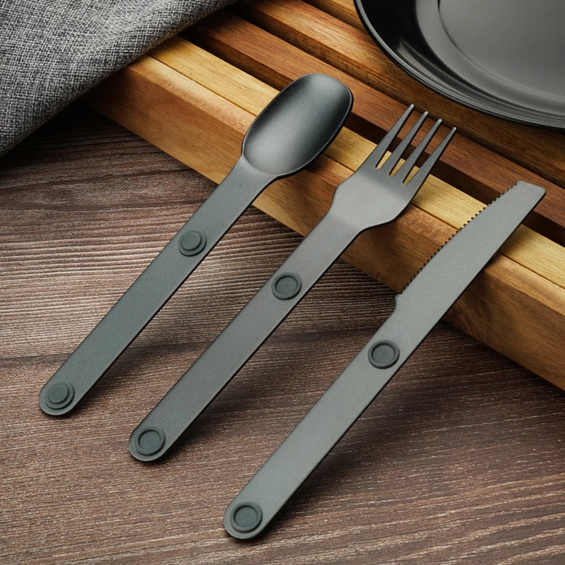 Set of gray kawaii utensils including spoon, fork, and knife on a wooden surface.