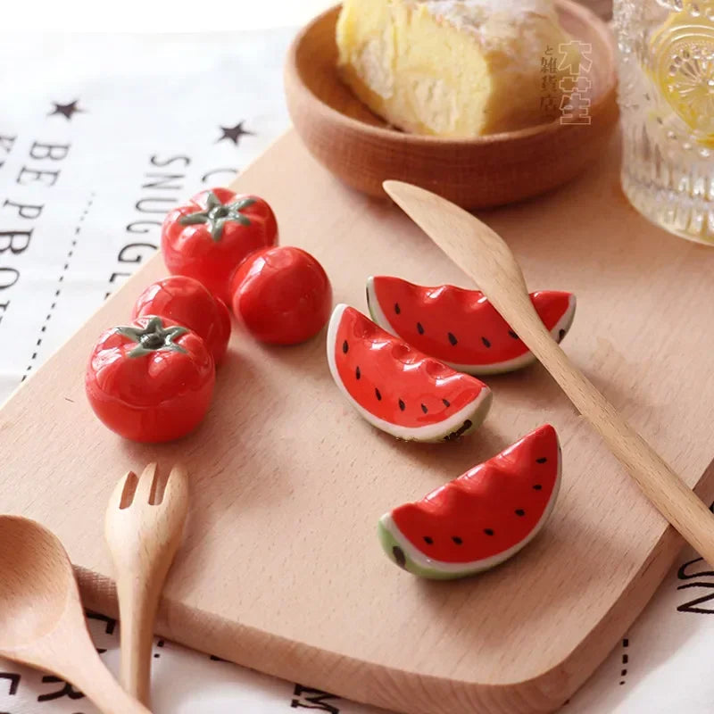 Kawaii ceramic red tomatoes and watermelon slices on a wooden board with a wooden spoon and fork.