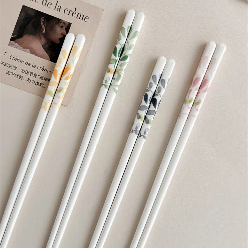 Set of four decorative kawaii chopsticks with floral patterns on a beige background.