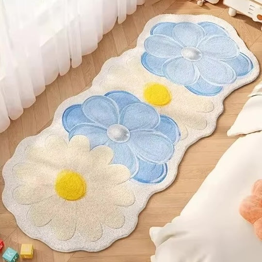 A rug with four flowers in blue and cream on a wooden floor.
