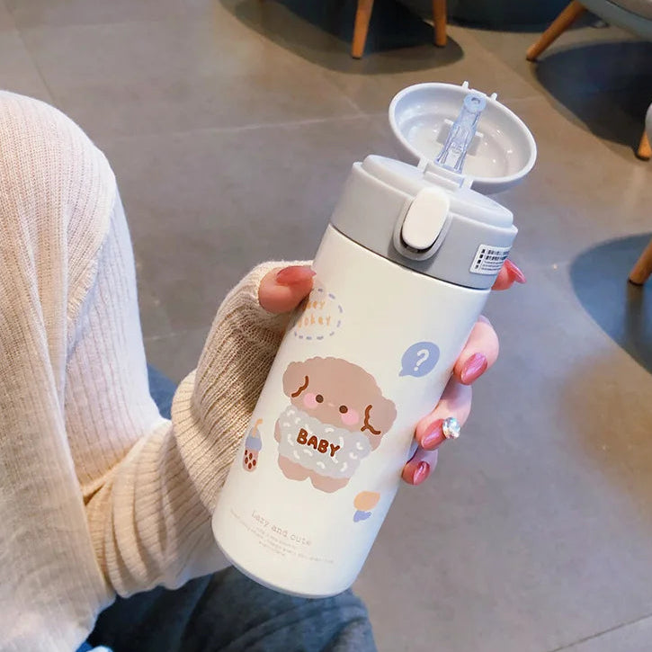 Person holding a white kawaii water bottle with a cartoon design in an indoor setting