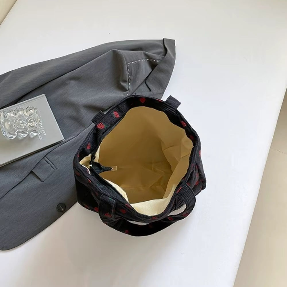 A top down view of the inside of a black tote bag with a strawberry print