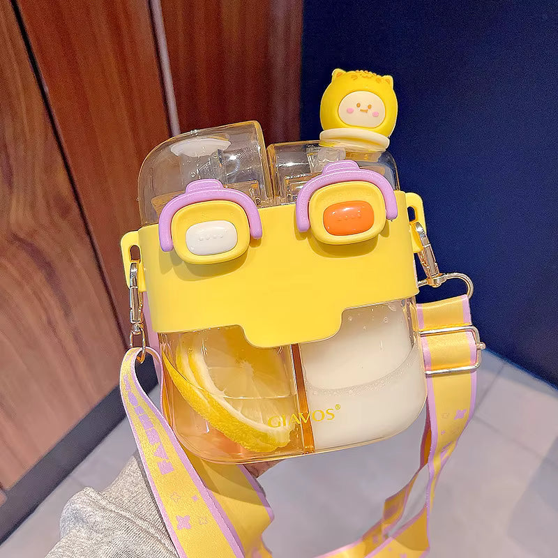 Yellow cartoon-style kawaii water bottle with clear sections and a small yellow character on top, against a wooden and blue wall background.
