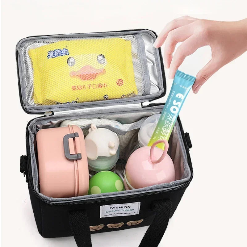 Black kawaii lunch bag with compartments containing various items, including a yellow towel and pink container.