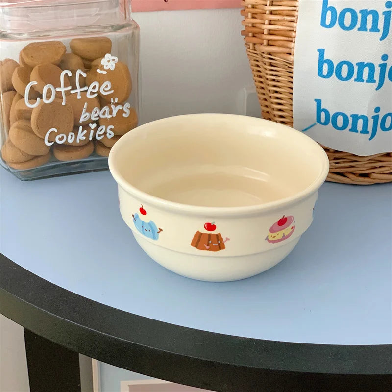 Beige kawaii ramen bowl with cartoon designs on a light blue surface, next to a jar labeled 'Coffee Bears Cookies' and a wicker basket.