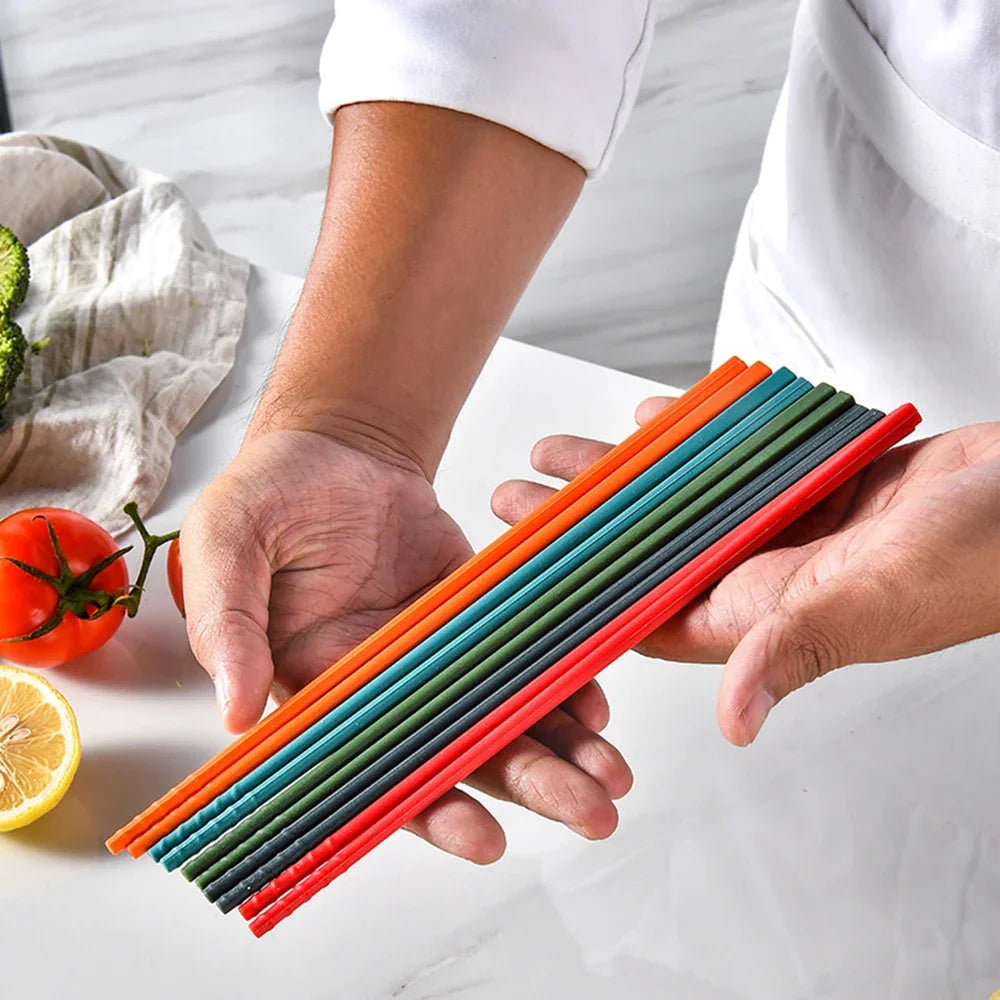 Colorful kawaii chopsticks held by a person with vegetables in the background