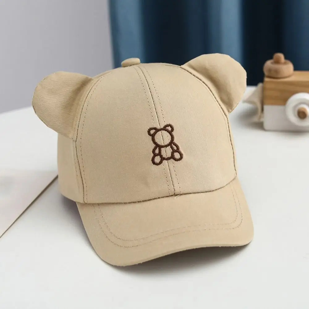 Beige Kawaii cap with bear ears and embroidered bear design on a white surface.
