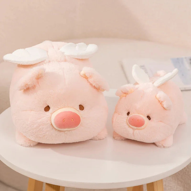 Two pink kawaii plush pigs with white wings on a round white table.