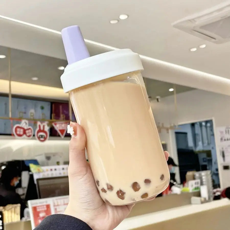 Hand holding a bubble tea kawaii cup with a straw in a store setting