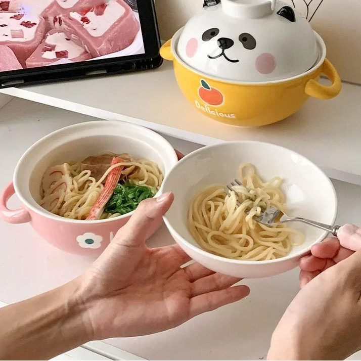 Two kawaii ramen bowls of instant noodles with cartoon animal-themed covers on a table.