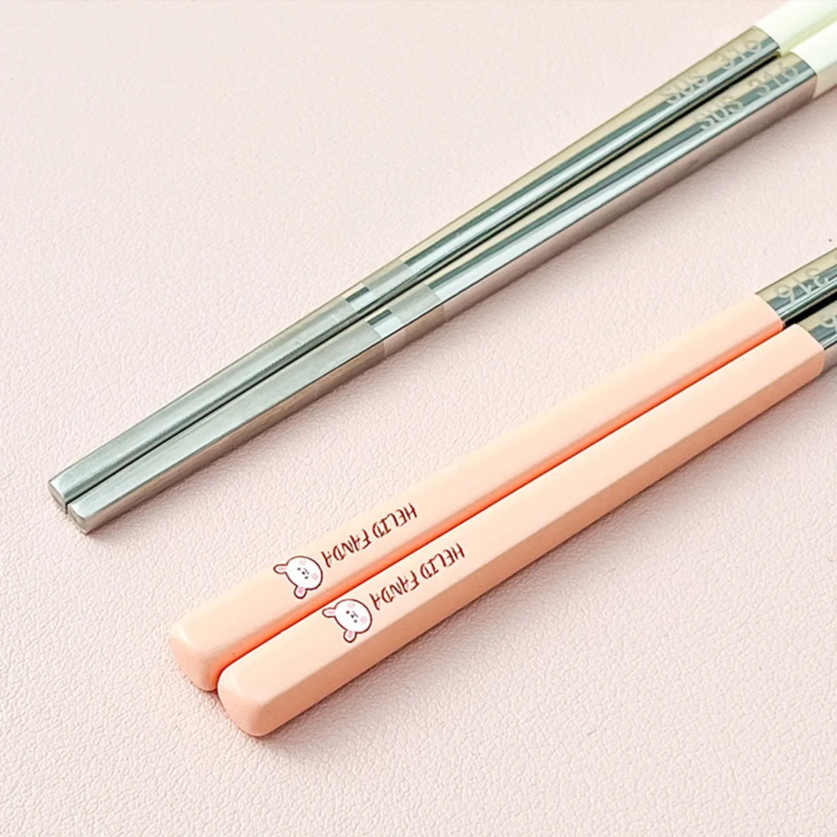Two sets of kawaii chopsticks, one silver and one peach-colored, on a light pink background.