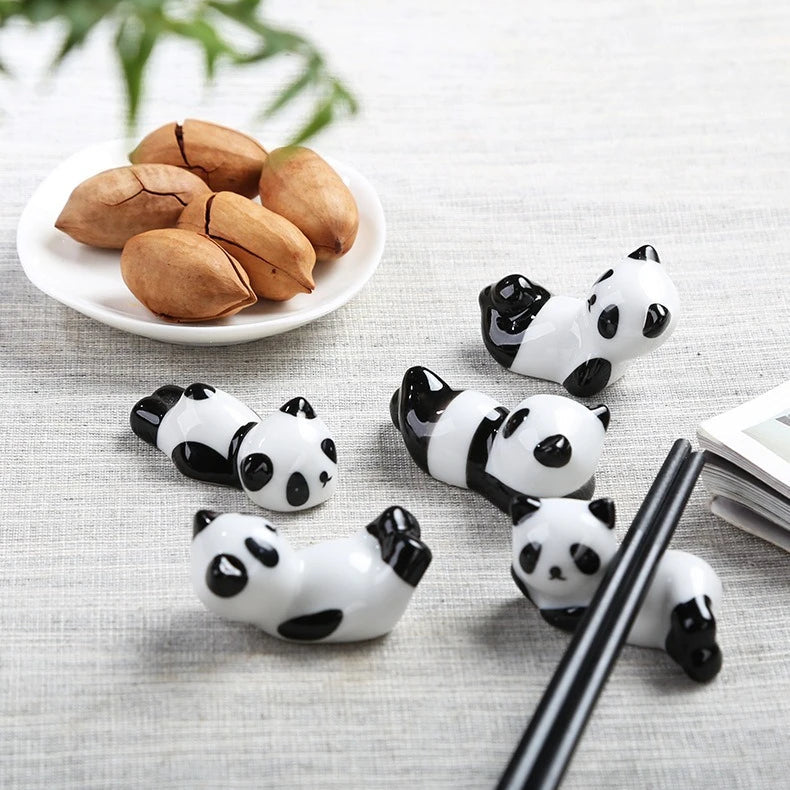 Panda-shaped kawaii chopstick holders on a gray surface with a plate of chestnuts.