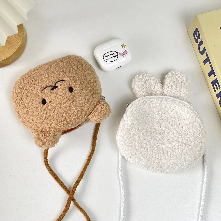 Two plush Kawaii toys, one brown and one white, on a light surface with a book in the background.