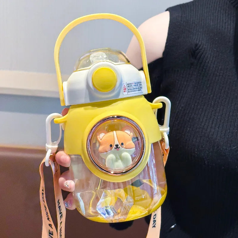 Clear kawaii water bottle with yellow lid and handle, featuring a cartoon character, held by a person.