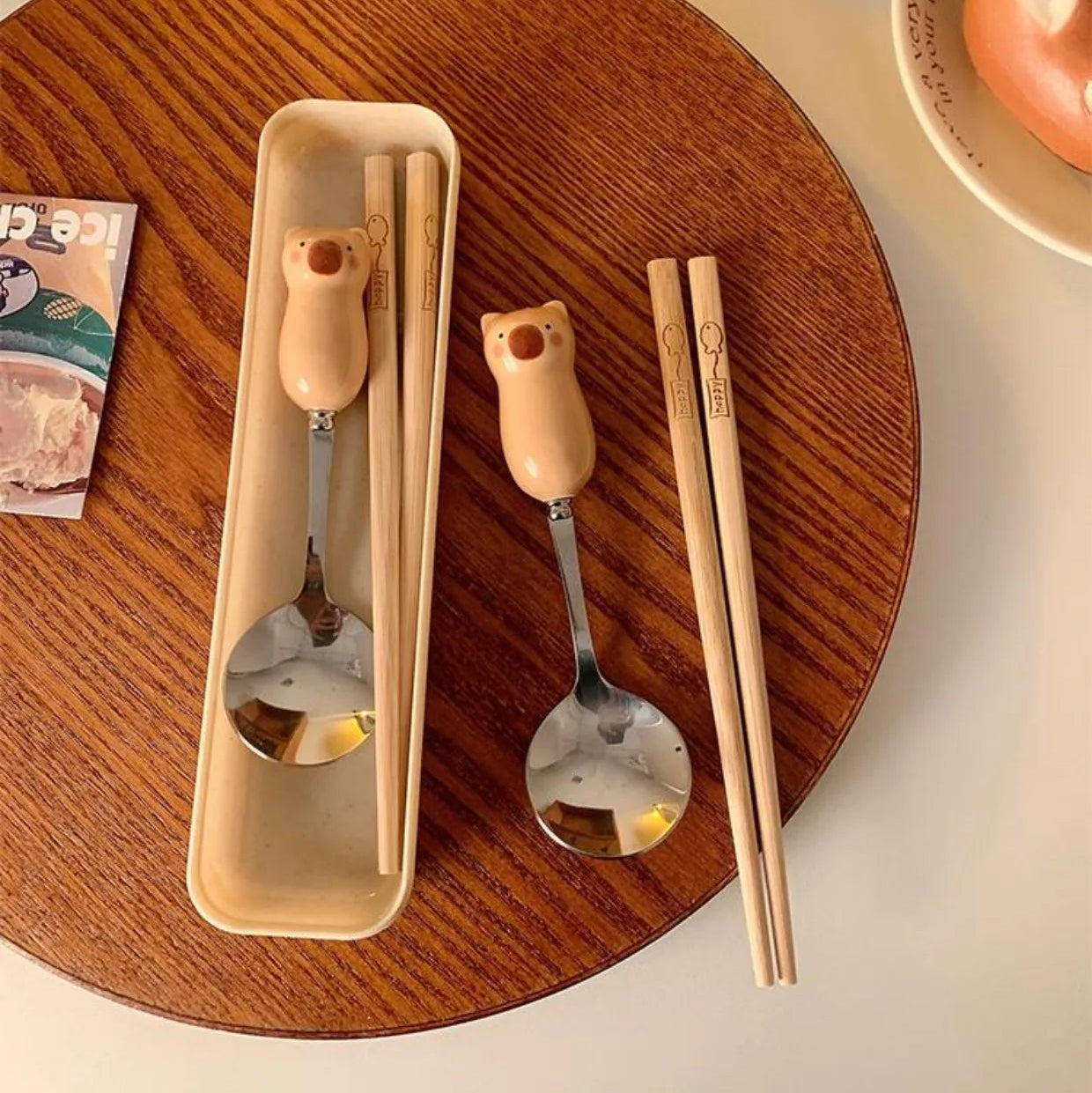 Kawaii utensils, and a holder on a wooden tray with a soft focus background.