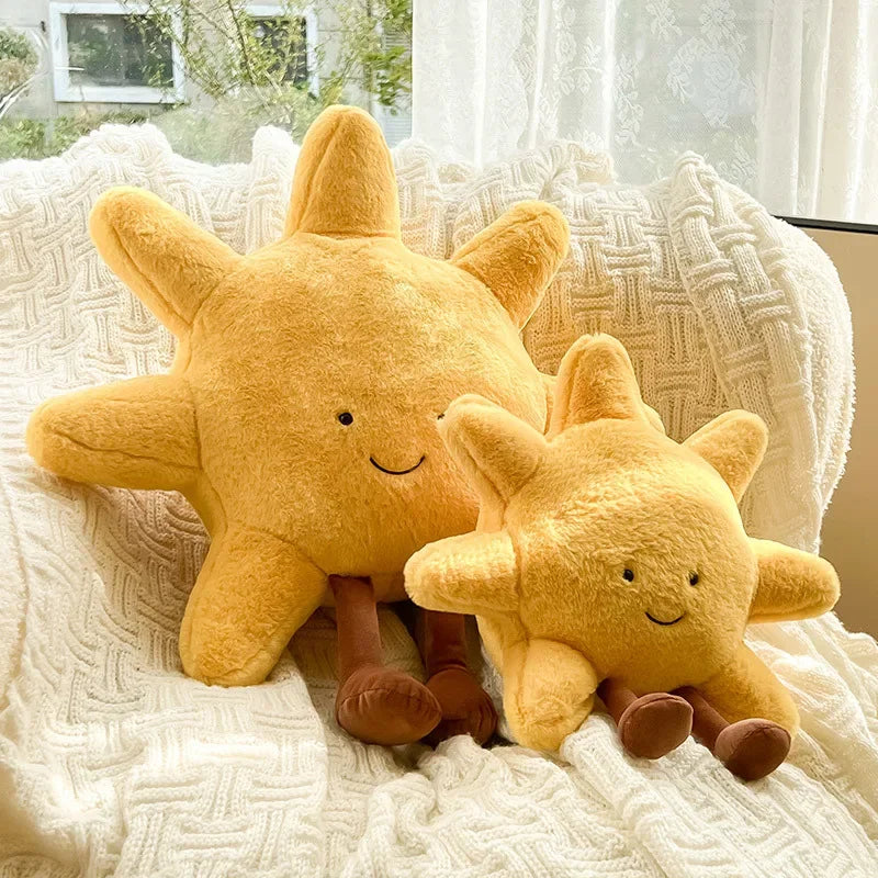 Two kawaii plush sun-shaped toys sitting on a textured surface with a window in the background.