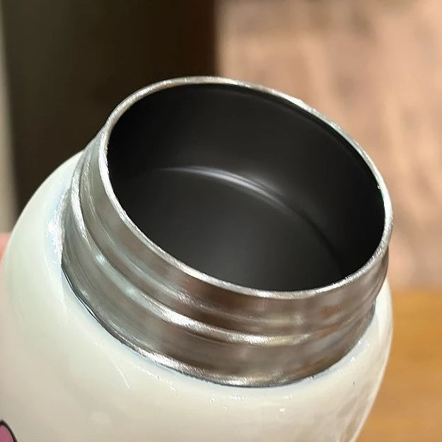 Close-up of a kawaii white bottle with a silver cap on a wooden surface.