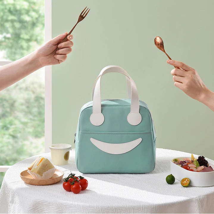 Light blue kawaii lunch bag with smiley face design on a table with hands holding forks above.