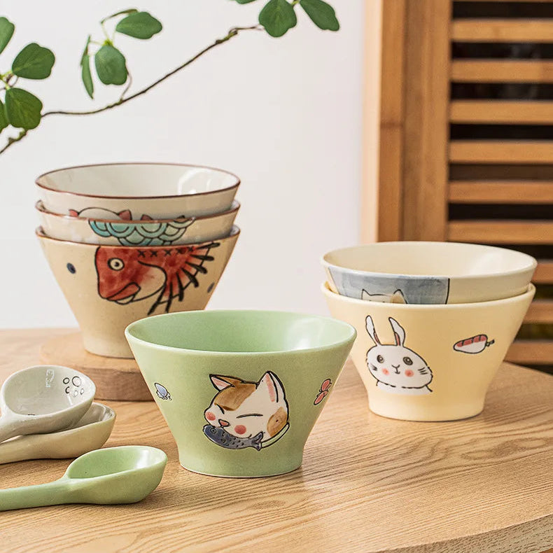 Set of ceramic kawaii ramen bowls with animal illustrations on a wooden surface