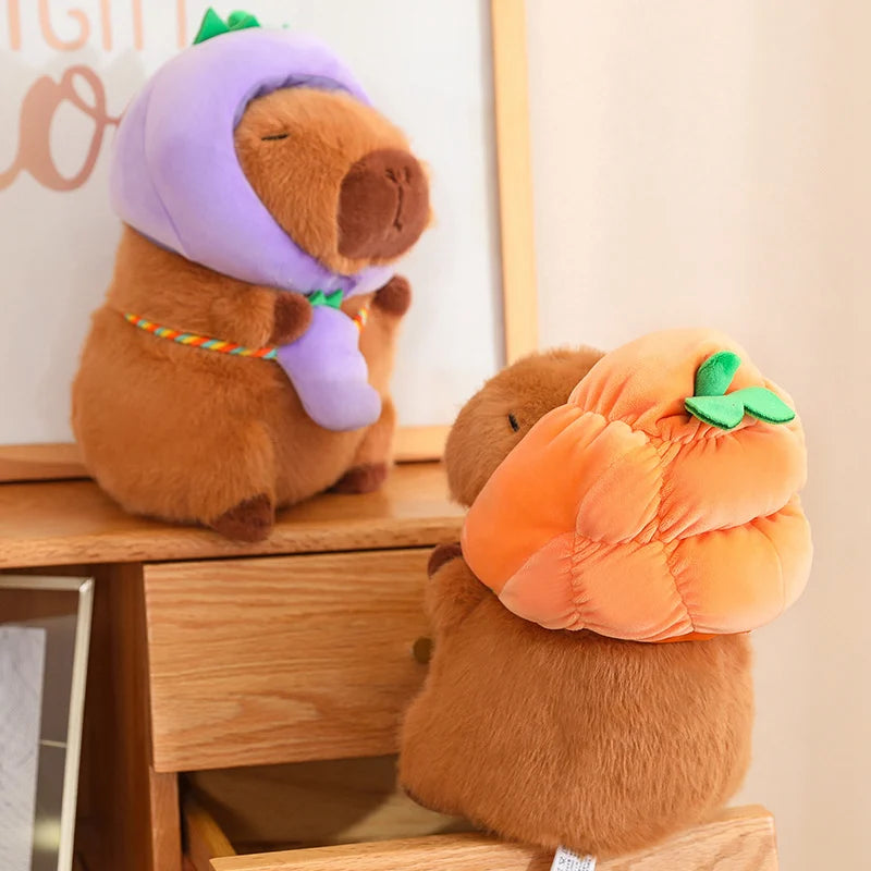 Two kawaii plush toys, one resembling a bear with a purple hat and the other a pumpkin, sitting on a wooden surface.