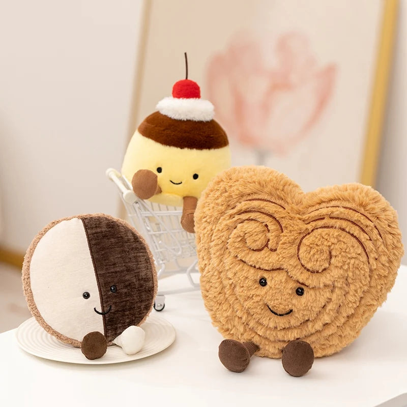 Three cute kawaii plush toys shaped like a cookie, a cake, and a hedgehog on a white surface.
