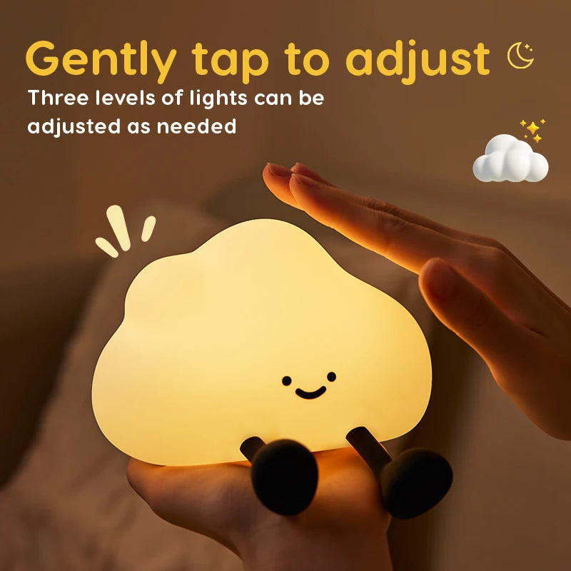 Hand holding a cloud-shaped kawaii night light with a smiling face, tapped by a finger, on a brown background.