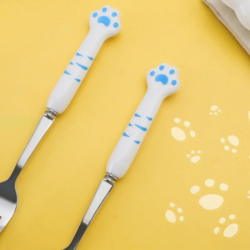 Kawaii utensils set with white handles featuring blue paw prints on a yellow background.