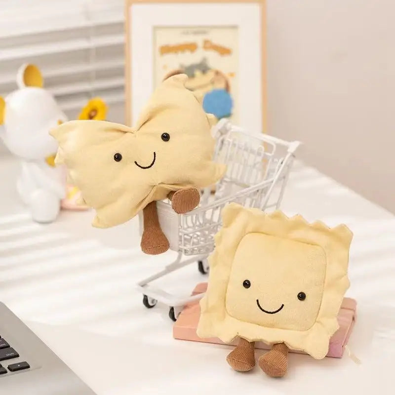 Two cute kawaii plush toys resembling pasta and a square-shaped food item on a desk.