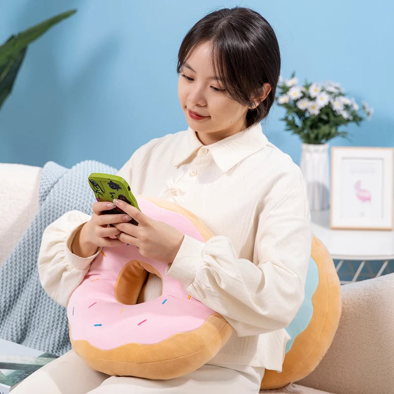 Woman sitting on a couch with a donut-shaped kawaii pillow and using a phone.